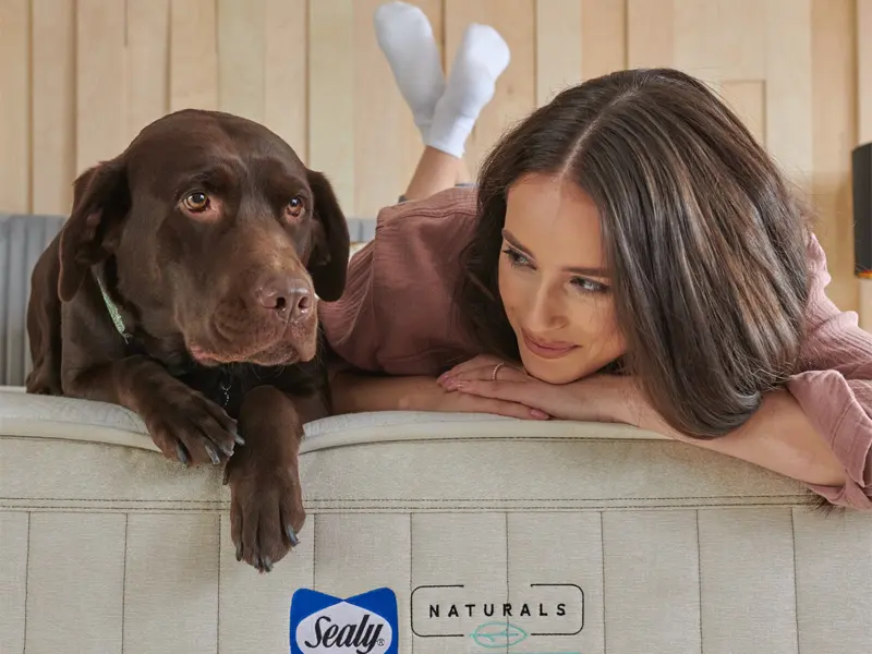 A photo of a woman and her dog on a new mattress from Mattress Mart